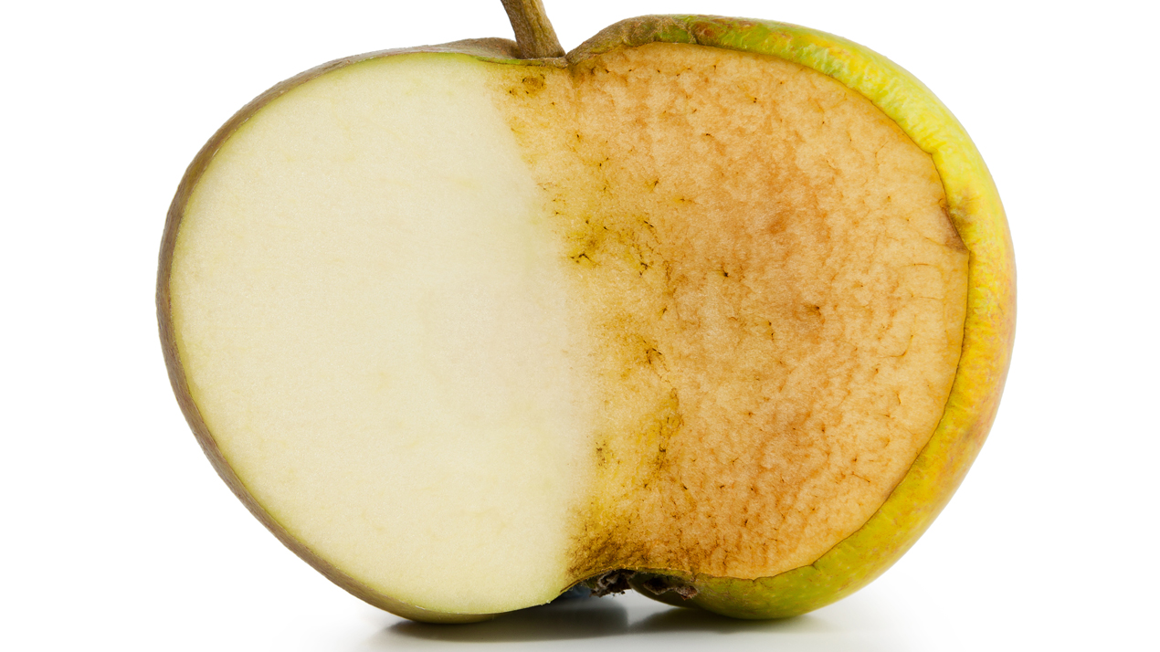 Ett delat äpple där vänster sida är ljust och höger sida är brunt.