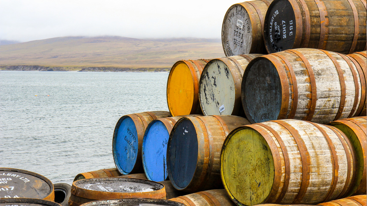 Hög stapel med ekfat i olika färger som ligger staplade på kajen på ön Islay.